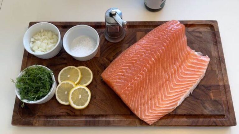 Laks klar til sous vide, med ingredienser, salt, peber, løg, dild og citron. 