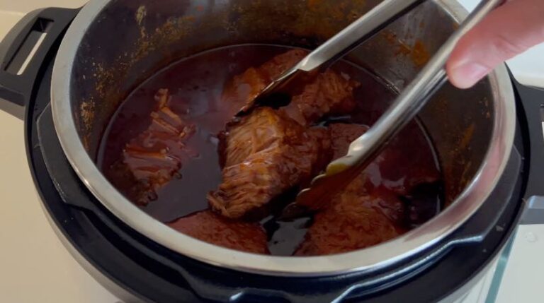 Færdigtilberedt Pulled pork i trykkoger, klar til at blive trukket fra hinanden.