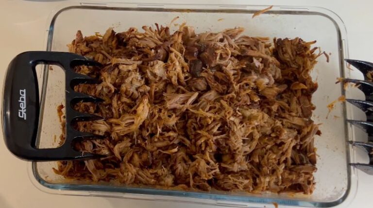 Pulled pork trukket fra hinanden i en glasskål med kødpullere.