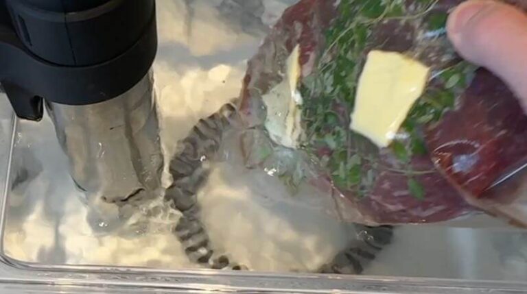 Oksemørbrad i sous vide-vandbad: Vakuumpakket oksemørbrad bliver sænket i et sous vide-vandbad ved 54 grader for perfekt tilberedning.