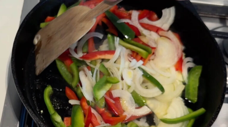 Peberfrugt og løg sauteres på en varm pande til fyldet i en klassisk Philly cheesesteak sandwich.