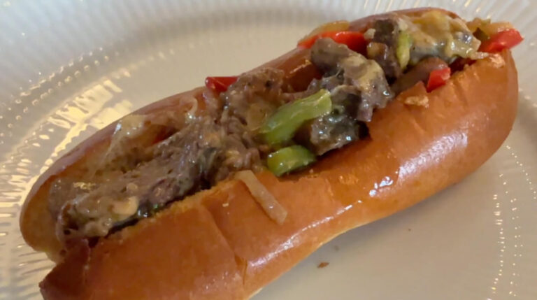 Philly cheesesteak sandwich serveret i brioche hotdogbrød med oksekød, ost og grøntsager.