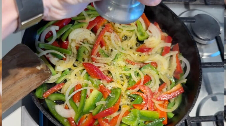 Friskkværnet peber tilsættes til løg og peberfrugt på panden.