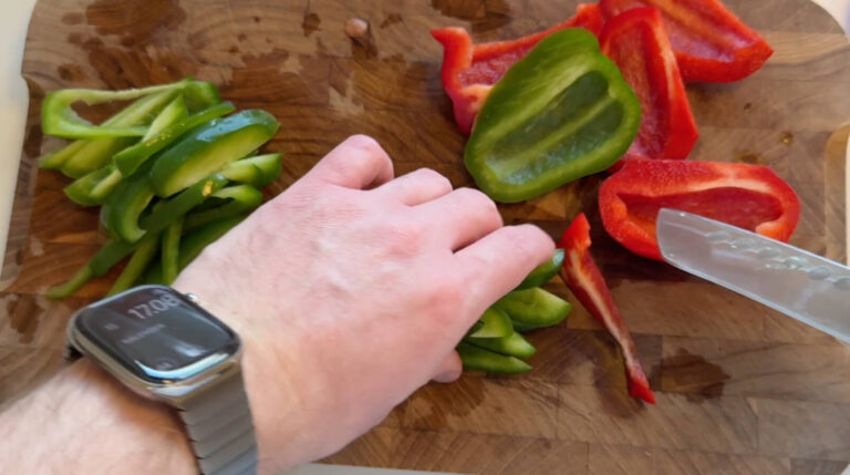 Grøn og rød peberfrugt skæres i tynde strimler til Philly cheesesteak sandwich.